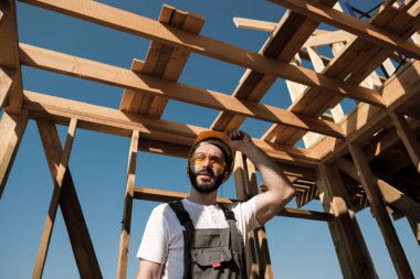 Adam bir ahşap çerçeve ev çatısında bir kurucusudur.