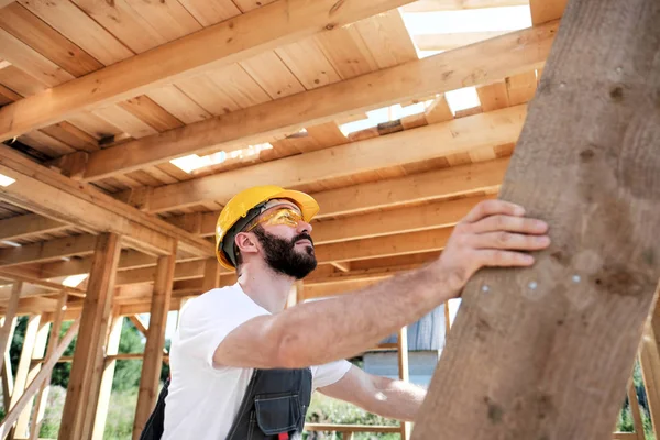 Adam bir ahşap çerçeve ev çatısında bir kurucusudur.