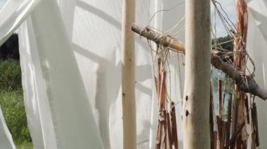 Beyaz keten kumaş ve ahşap direklerin sallanır rüzgarda üzerinde etnik dreamcatcher.