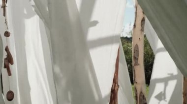 Ahşap direklerin üzerine beyaz keten kumaş sallanır rüzgarda.