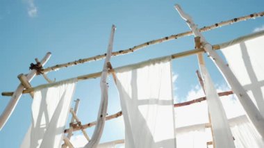 Ahşap direklerin üzerine beyaz keten kumaş sallanır rüzgarda.