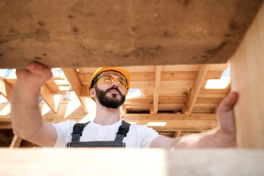 Adam bir ahşap çerçeve ev çatısında bir kurucusudur.