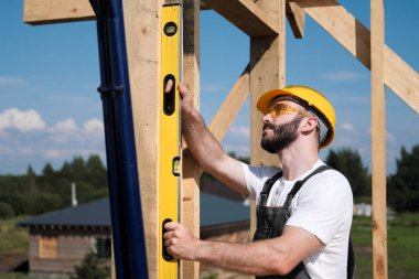 Adam bir ahşap çerçeve ev çatısında bir kurucusudur.