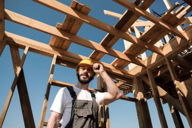 Adam bir ahşap çerçeve ev çatısında bir kurucusudur.