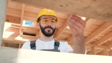 Adam bir ahşap çerçeve ev çatısında bir kurucusudur.