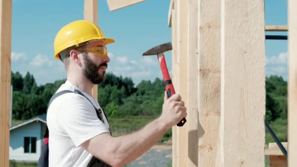 O homem é um construtor no telhado de uma casa de armação de madeira . — Vídeo de Stock