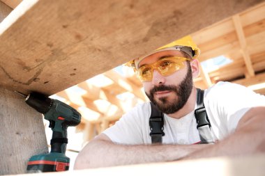 Adam bir ahşap çerçeve ev çatısında bir kurucusudur.