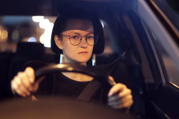 Genç kadın bir araba. Gece şehir ve sokak lambaları ışık.