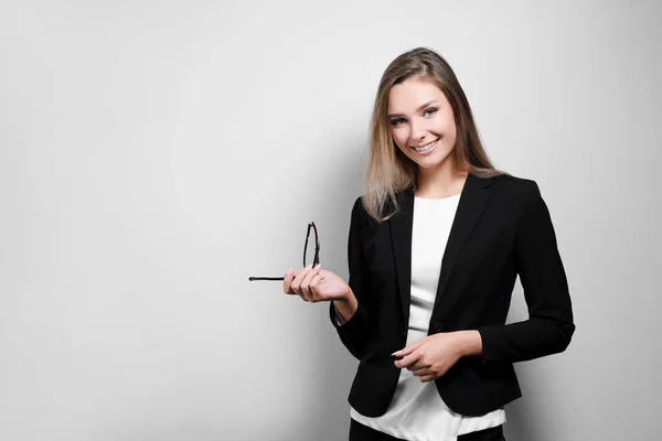 Retrato de una hermosa mujer sonriente con gafas en un traje de negocios y chaqueta sobre un fondo blanco . — Foto de Stock