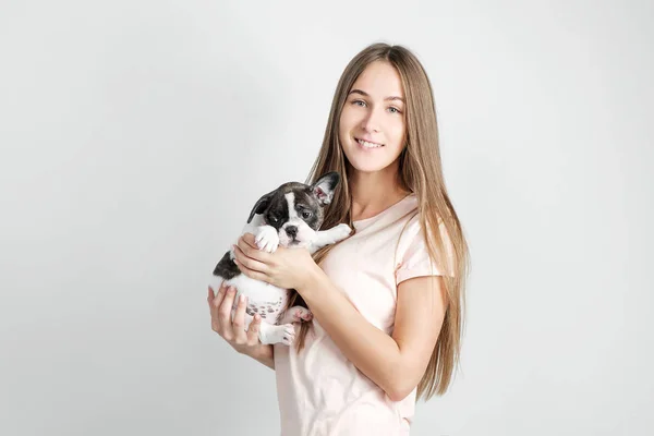 Ein schönes junges Mädchen hält den Welpen einer französischen Bulldogge. — Stockfoto