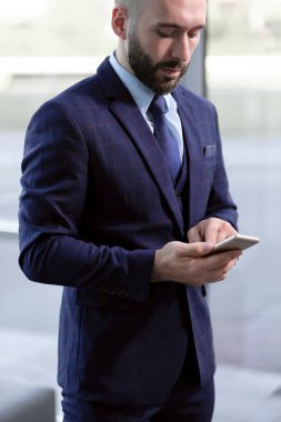 Yakışıklı erkek işadamı bir smartphone bir ofis binasının arka plan üzerinde kullanır..