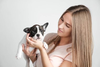 Güzel bir genç kız bir Fransız bulldog yavru tutuyor.