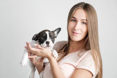 Güzel bir genç kız bir Fransız bulldog yavru tutuyor.