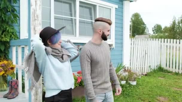 Молодая семья, мужчина и женщина на фоне синего деревянного деревенского дома . — стоковое видео