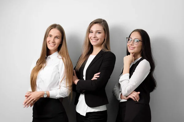 Drie mooie jonge vrouw in zakelijke kleding op een witte achtergrond te glimlachen. — Stockfoto
