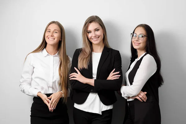 Drie mooie jonge vrouw in zakelijke kleding op een witte achtergrond te glimlachen. — Stockfoto