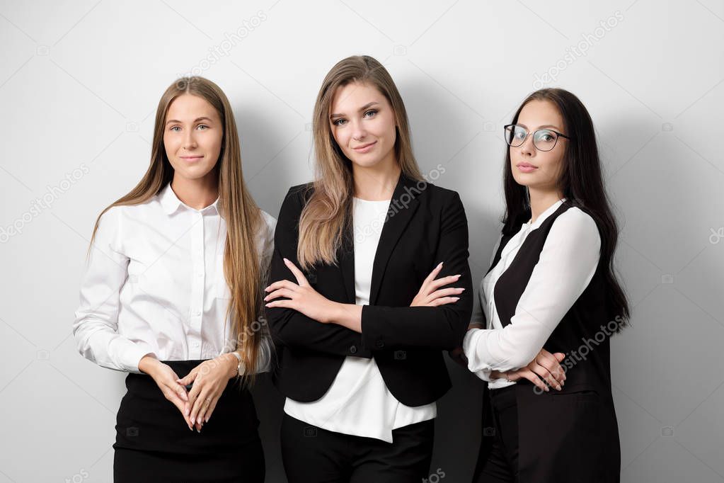 Three beautiful young smiling woman in business clothes on a white background.