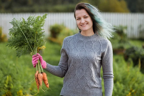 A girl with colored hair, a farmer holding a fresh carrot.