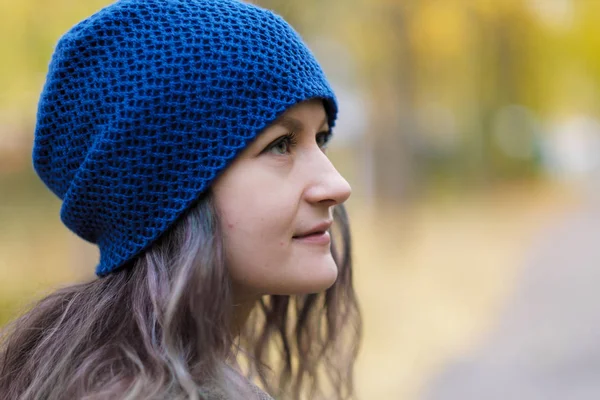 A menina em um casaco e chapéu azul em um contexto de árvores de outono e folhas de bordo . — Fotografia de Stock