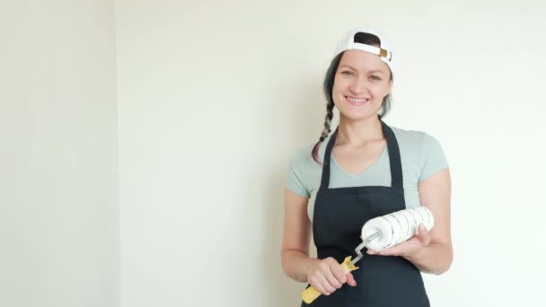 Schilderen muren met roller. Een jonge vrouw schilderen muren in beige in haar huis met een roller. Close-up. — Stockvideo