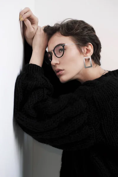 Joven hermosa chica con pelo rizado corto en gafas y ropa casual negro, retrato de estudio . —  Fotos de Stock