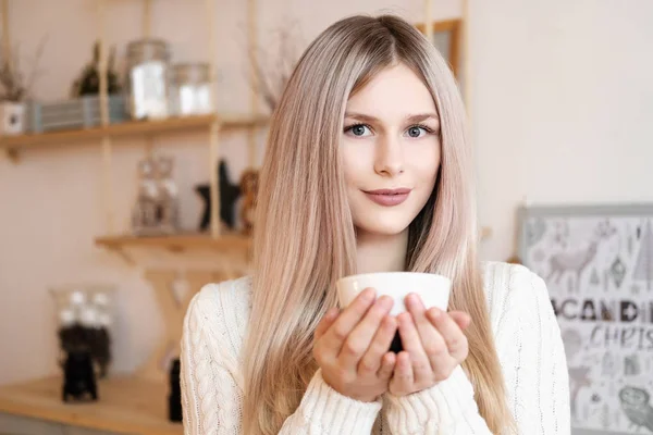 Gros plan fille blonde avec une tasse de boisson chaude, thé ou café, à la maison dans une chambre confortable . — Photo