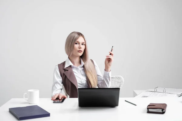Blond meisje in een pak werkt op een computer in een witte lichte kantoor. — Stockfoto