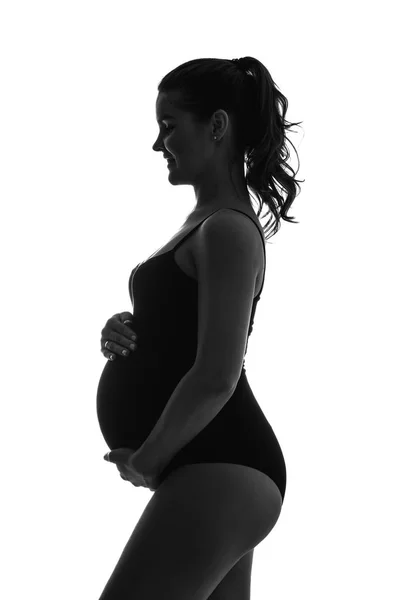 Silhouette noire et blanche d'une jeune fille enceinte. Tient un ventre et sourit . — Photo