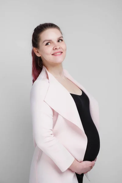 Junge schwangere Frau im Business-Freizeitanzug auf weißem Hintergrund. — Stockfoto