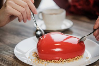 Kırmızı bir kalp şeklinde masaya pastadır. Kaşık, erkek ve kadın, iki elinle bir pasta streç.