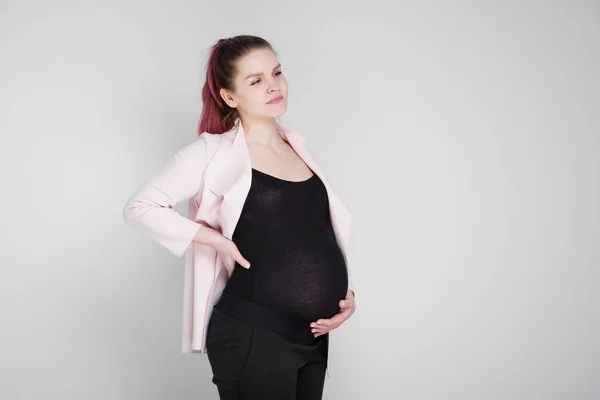 Těhotná dívka drží na zádech. Bolest, tíha v zádech. — Stock fotografie