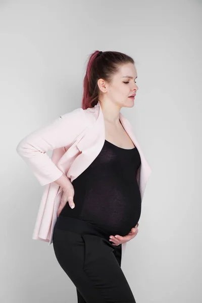 Chica embarazada aferrada a su espalda. Dolor, pesadez en la espalda . — Foto de Stock
