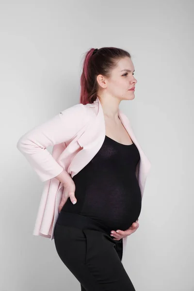 Une fille enceinte s'accrochant à son dos. Douleur, lourdeur dans le dos . — Photo