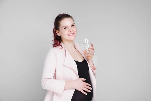 Een zwanger meisje houdt een glas water en drinken. — Stockfoto