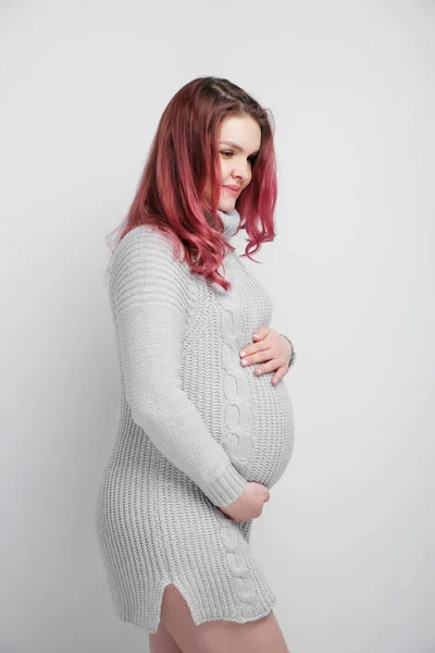 Μια έγκυος γυναίκα με χρώμα βυσσινί μαλλιών σε ένα γκρι πλεκτό πουλόβερ. — Φωτογραφία Αρχείου