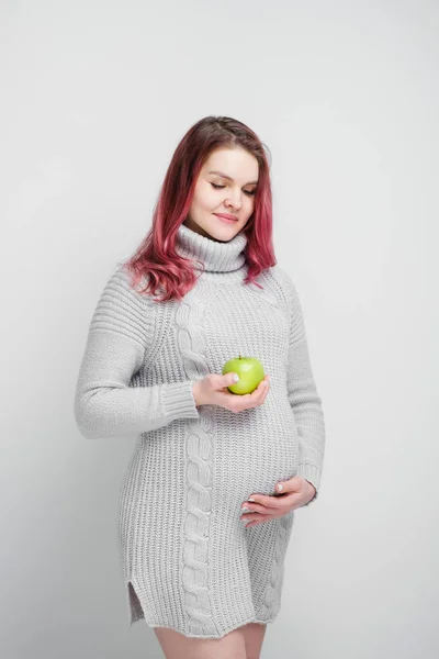 Kobieta w ciąży jest gospodarstwa zielone i czerwone jabłka. — Zdjęcie stockowe