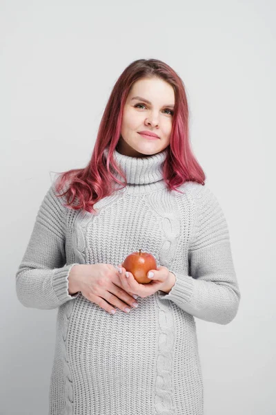 Una mujer embarazada sostiene manzanas verdes y rojas . —  Fotos de Stock