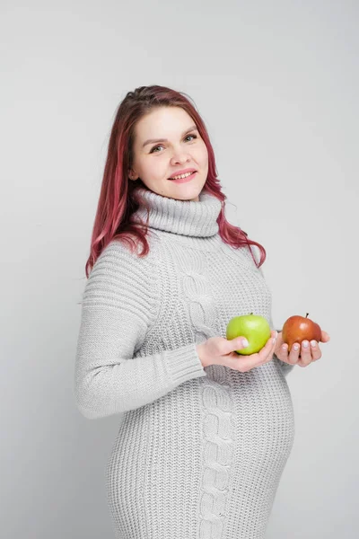 Těhotná žena drží zelená a červená jablka. — Stock fotografie