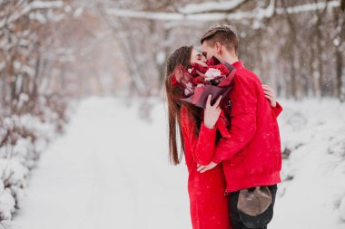Sevgili benim park ile tarihi kış. Bir buket kırmızı çiçek, yürümek, kucaklama, öpücük, romantik bir ortamda gülmek. Bir çift, karı ve koca portresi. Kırmızı ceket ve Mont.