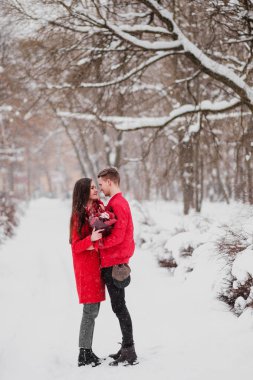 Sevgili benim park ile tarihi kış. Bir buket kırmızı çiçek, yürümek, kucaklama, öpücük, romantik bir ortamda gülmek. Bir çift, karı ve koca portresi. Kırmızı ceket ve Mont.