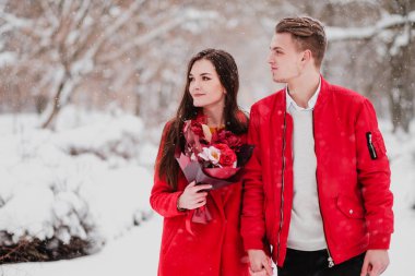 Sevgili benim park ile tarihi kış. Bir buket kırmızı çiçek, yürümek, kucaklama, öpücük, romantik bir ortamda gülmek. Bir çift, karı ve koca portresi. Kırmızı ceket ve Mont.