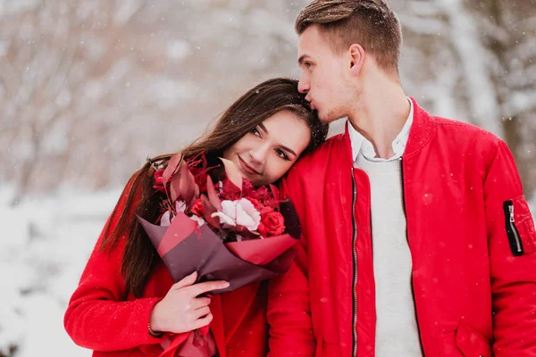 Sevgili benim park ile tarihi kış. Bir buket kırmızı çiçek, yürümek, kucaklama, öpücük, romantik bir ortamda gülmek. Bir çift, karı ve koca portresi. Kırmızı ceket ve Mont.
