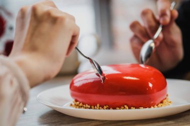 Kırmızı bir kalp şeklinde masaya pastadır. Kaşık, erkek ve kadın, iki elinle bir pasta streç.