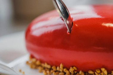 Kırmızı bir kalp şeklinde masaya pastadır. Kaşık, erkek ve kadın, iki elinle bir pasta streç.