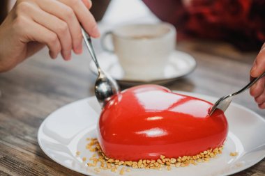 Kırmızı bir kalp şeklinde masaya pastadır. Kaşık, erkek ve kadın, iki elinle bir pasta streç.