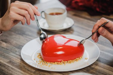 Kırmızı bir kalp şeklinde masaya pastadır. Kaşık, erkek ve kadın, iki elinle bir pasta streç.