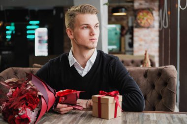 Genç bir adam bir restoranda oturur ve bir kız arkadaş, kız arkadaşı veya karısı ile bir toplantı için bekliyor. Çiçek ve hediye yakınındaki, saat bakarak vardır.
