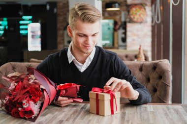 Genç bir adam bir restoranda oturur ve bir kız arkadaş, kız arkadaşı veya karısı ile bir toplantı için bekliyor. Çiçek ve hediye yakınındaki, saat bakarak vardır.