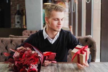 Genç bir adam bir restoranda oturur ve bir kız arkadaş, kız arkadaşı veya karısı ile bir toplantı için bekliyor. Çiçek ve hediye yakınındaki, saat bakarak vardır.