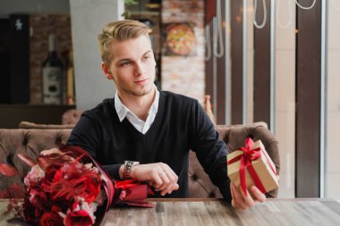 Genç bir adam bir restoranda oturur ve bir kız arkadaş, kız arkadaşı veya karısı ile bir toplantı için bekliyor. Çiçek ve hediye yakınındaki, saat bakarak vardır.